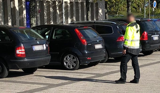 Foto: Lars Laursen - en parkeringsvagt benytter sin mobiltelefon til at at tage fotos af de parkerede biler ved Seniorklubberne.